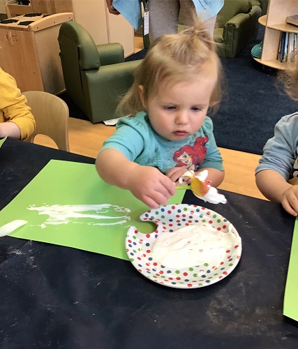 A toddler painting with flowers