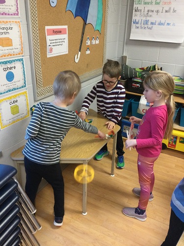 Children playing table hockey with sticks they made