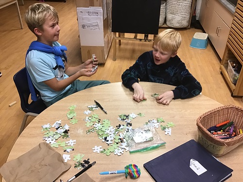 two children at a table doing a puzzle