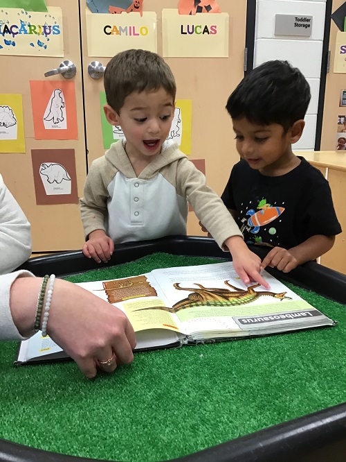 two children looking at a dinosaur book