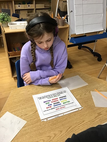 one school age child sitting at the table reading through the colour test page