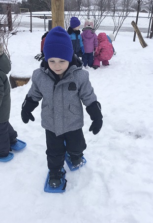 Preschool boy walking in snow shoes