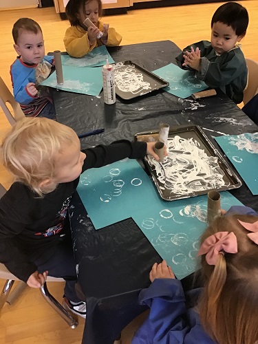 Toddlers painting with tubes and white paint