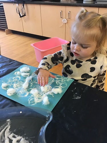 Toddler girl creating snow scene