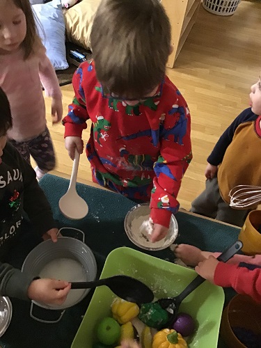 A child adding flour to a bowl of play food