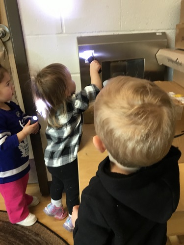 Children shining a flashlight on a picture of a groundhog