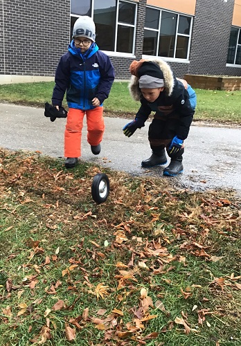Children rolling a wheel down a small hill