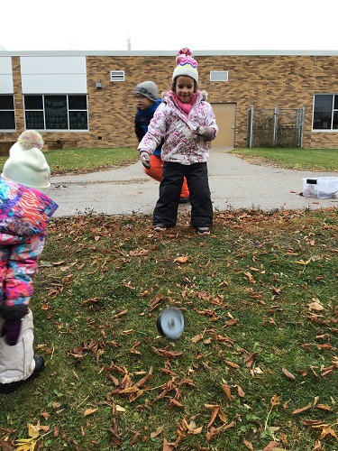 A child rolling a wheel down a small hill