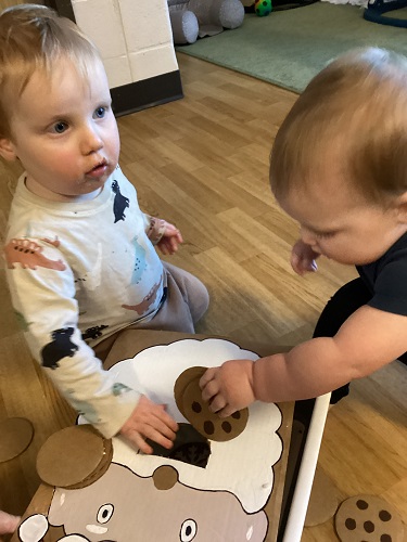 Two infants feeding a cardboard Santa cookies