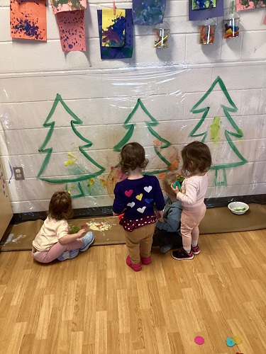 Children painting trees on an art wall