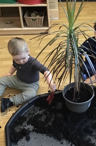 A child scooping soil into a pot
