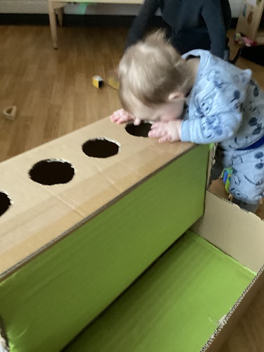An infant looking into a cardboard ball drop