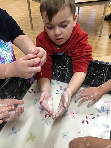 Children putting their hands into oobleck