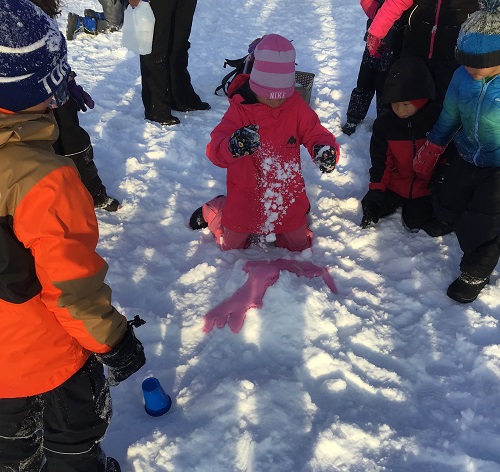 Children standing around a snow volcano outside