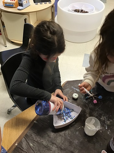 Children at a table making snowflakes with glitter and popsicle sticks