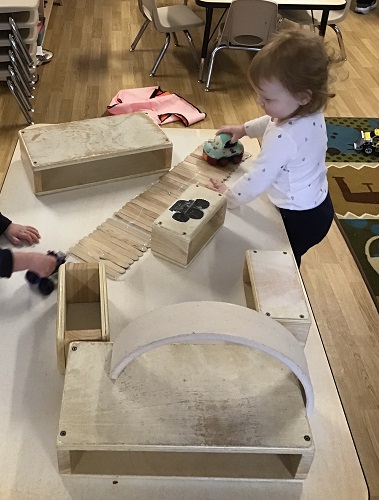 A child driving a car around a track created on the table