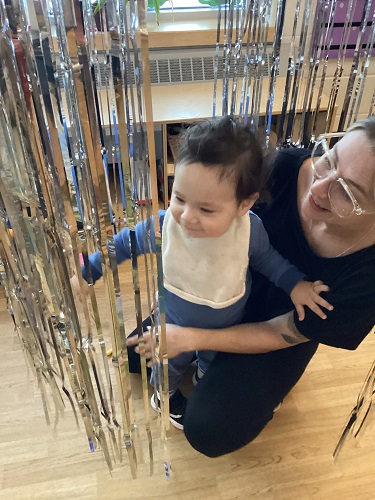 An educator and child surrounded by hanging tinsel