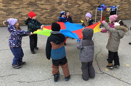 Children in a circle holding a parachute