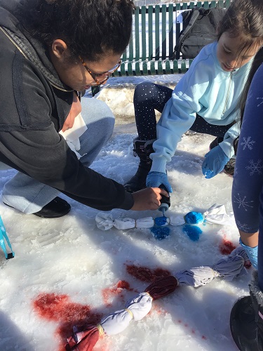 An educator and a children pouring dye on a shirt outside