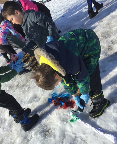 Children spraying dye on their tied up shirts in the snow