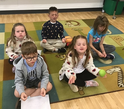 Children sitting on a carpet doing a guided mediation