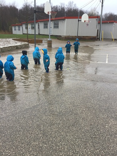 A group od children walking through a giant puddle