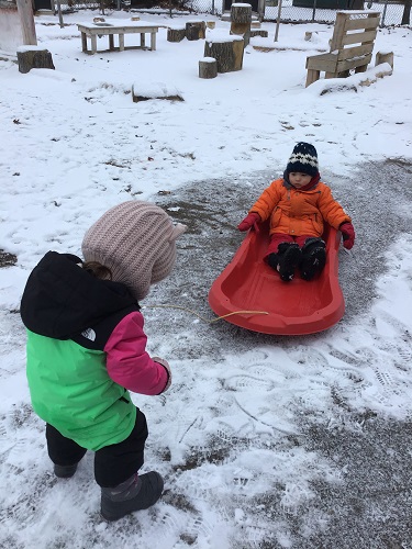 toddler girl pulling boy in sled