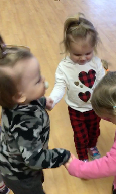 3 toddlers dancing in a circle together 