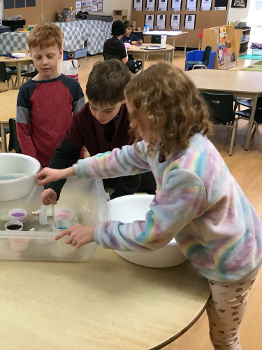 School-age children making potions with water 