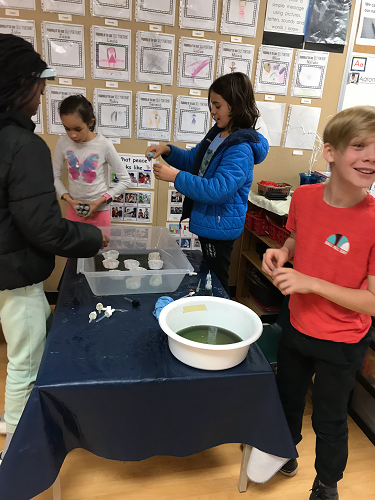Group of school-age peers at a table mixing colours