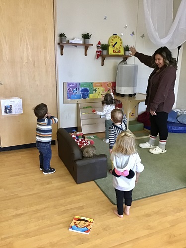 Toddler educator and children finding elf