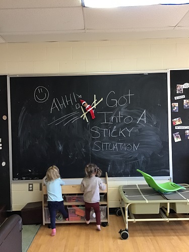 Toddlers finding elf on black board