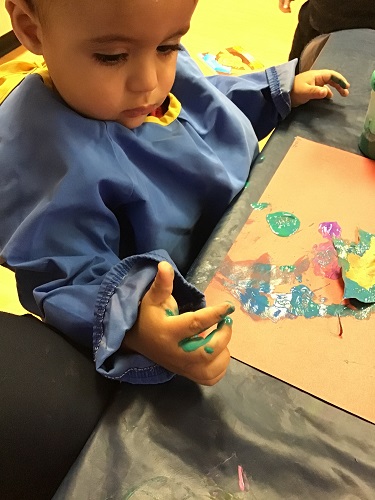 Toddler boy painting with a leaf