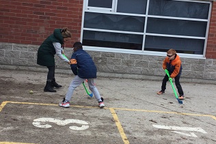 Educator playing hockey with 2 school-age boys