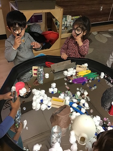 Two preschool children using magnify glasses