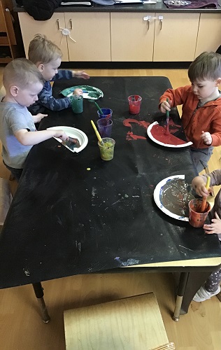 Group of preschool friends painting paper plate rainbow