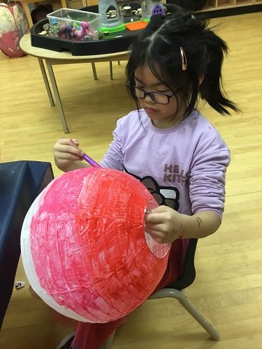 school-age girl painting a chinese lantern  