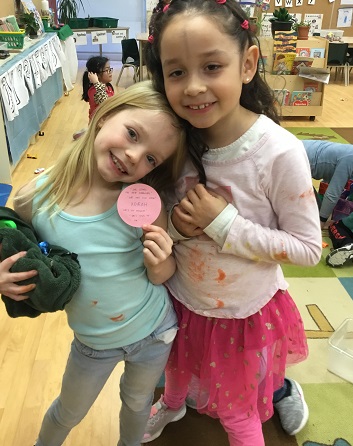 2 school-age girls posing with their note of friendship 