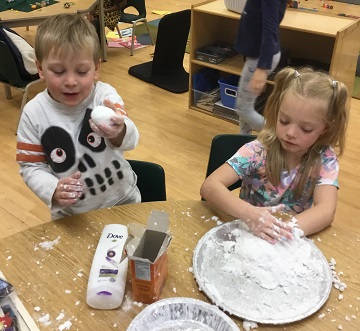 School-age boy and girl making snow balls out of fake snow 