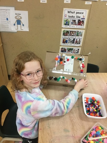 School-age girl making cardboard gingerbread house 