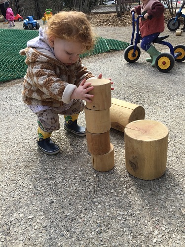 A toddler is building a tower with some blocks.