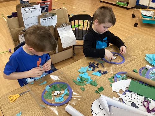 2 school age children working on their world sun catchers