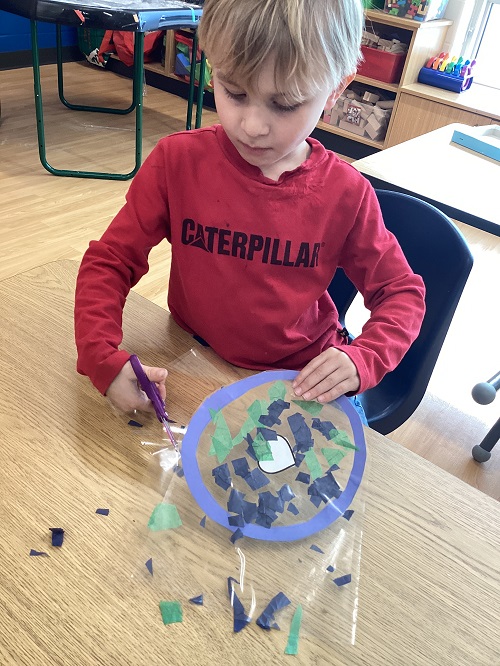 A school age child working on their world sun catcher