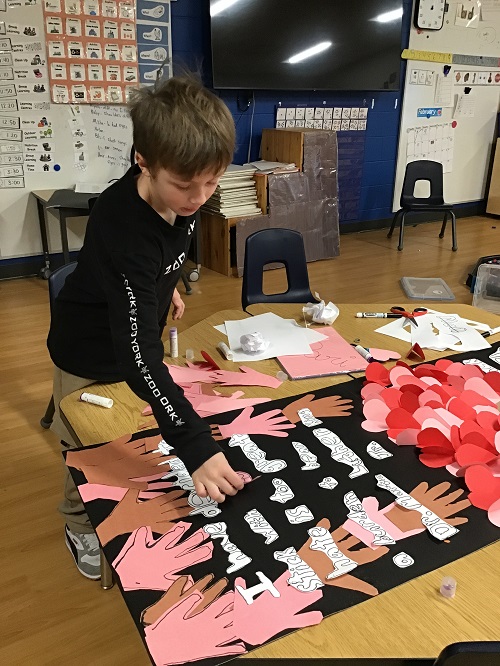 A school age child working on a group poster highlighting Black History Month