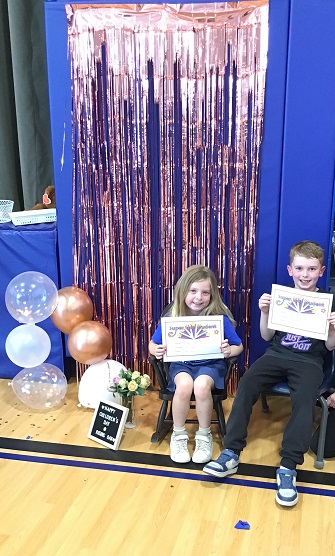 2 school age children showing off their Superstar certificates