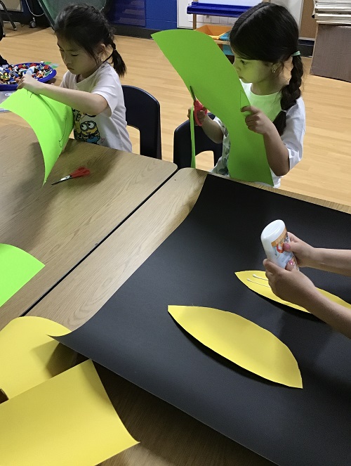 2 school age children cutting paper