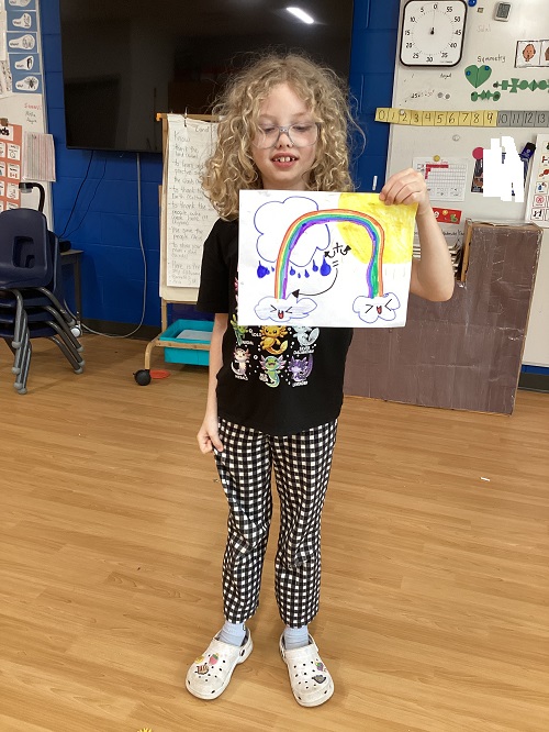A school age child showing off art work