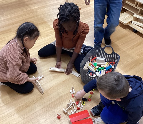 A group of children play wiht train tracks
