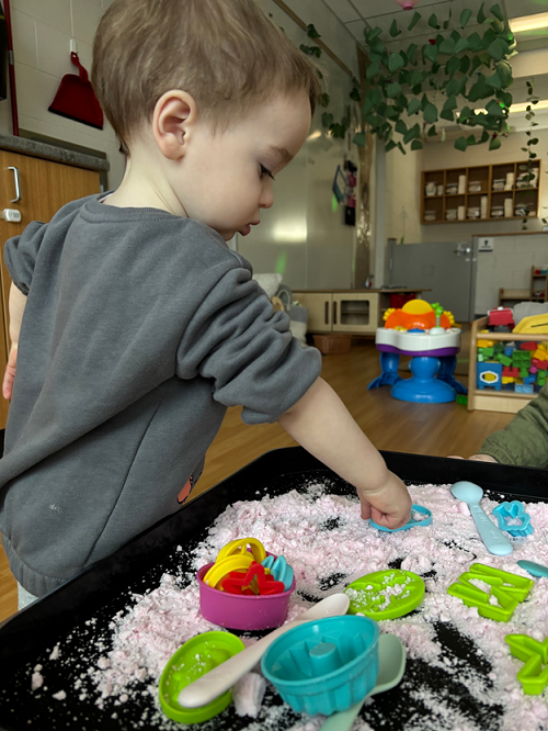 A child exploring with tools in cloud dough.