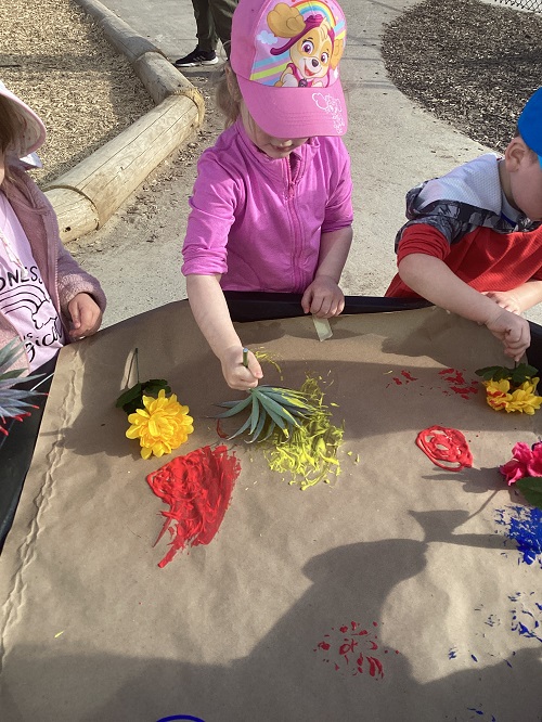 A small group of children painting with flowers
